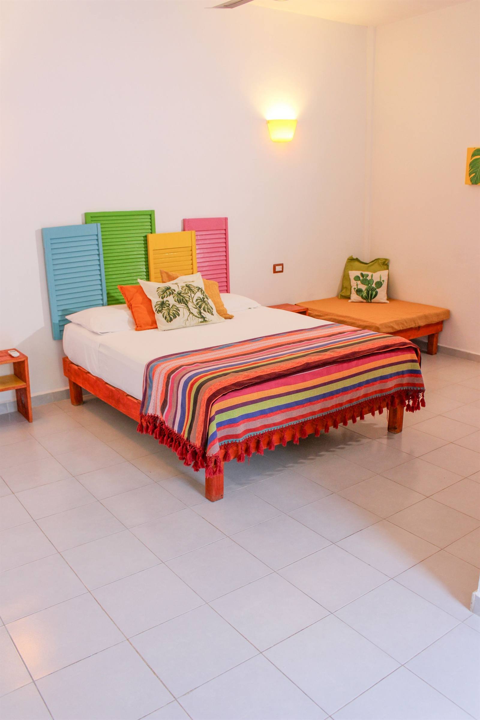 Comfort double room with colorful headboards and a cushioned bench